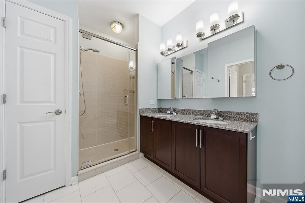 Bathroom with a glass-enclosed shower and double-sink dark wood vanity.