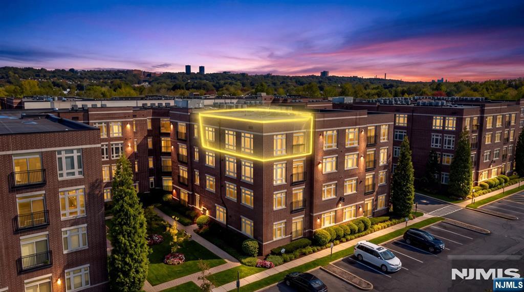 Brick apartment building at dusk with one upper corner unit outlined in yellow.