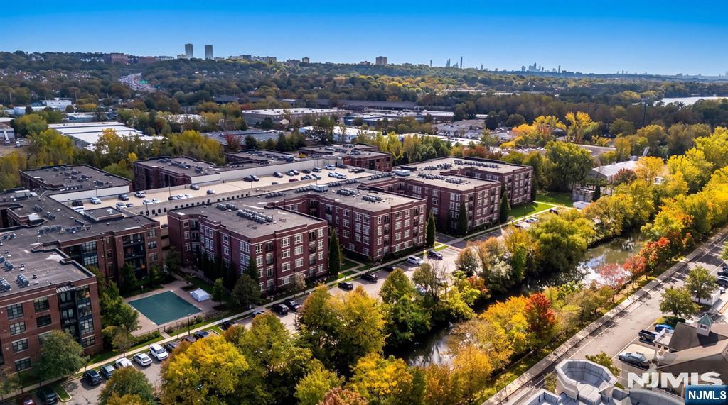 Aerial view of brick apartment buildings surrounded by parking lots and colorful autumn trees.