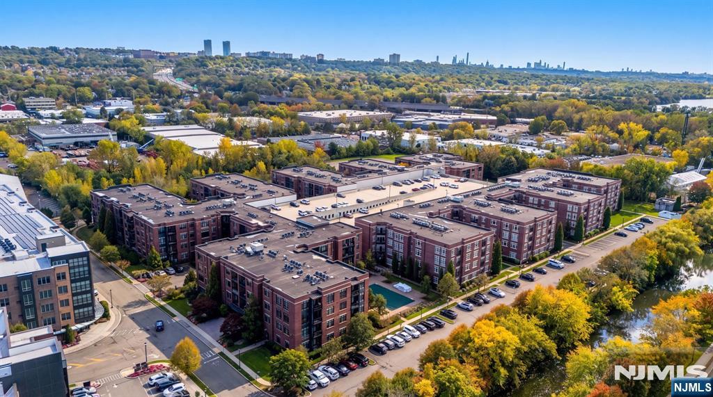 Aerial view of a brick residential complex with parking lots, autumn trees, and a distant skyline.