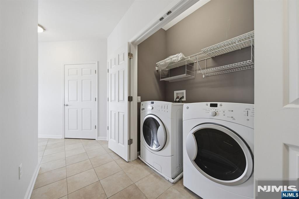 Laundry room with a front-loading washer and dryer beneath wire shelving.