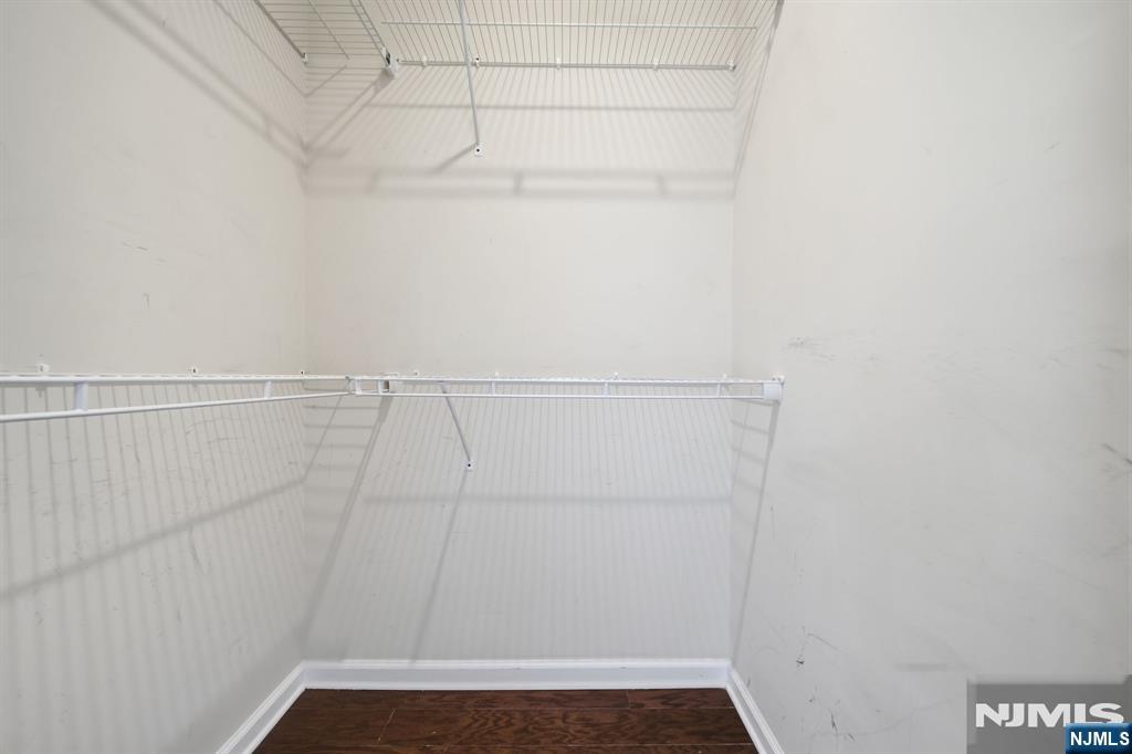 Empty walk-in closet with white wire shelving and a dark wood floor.