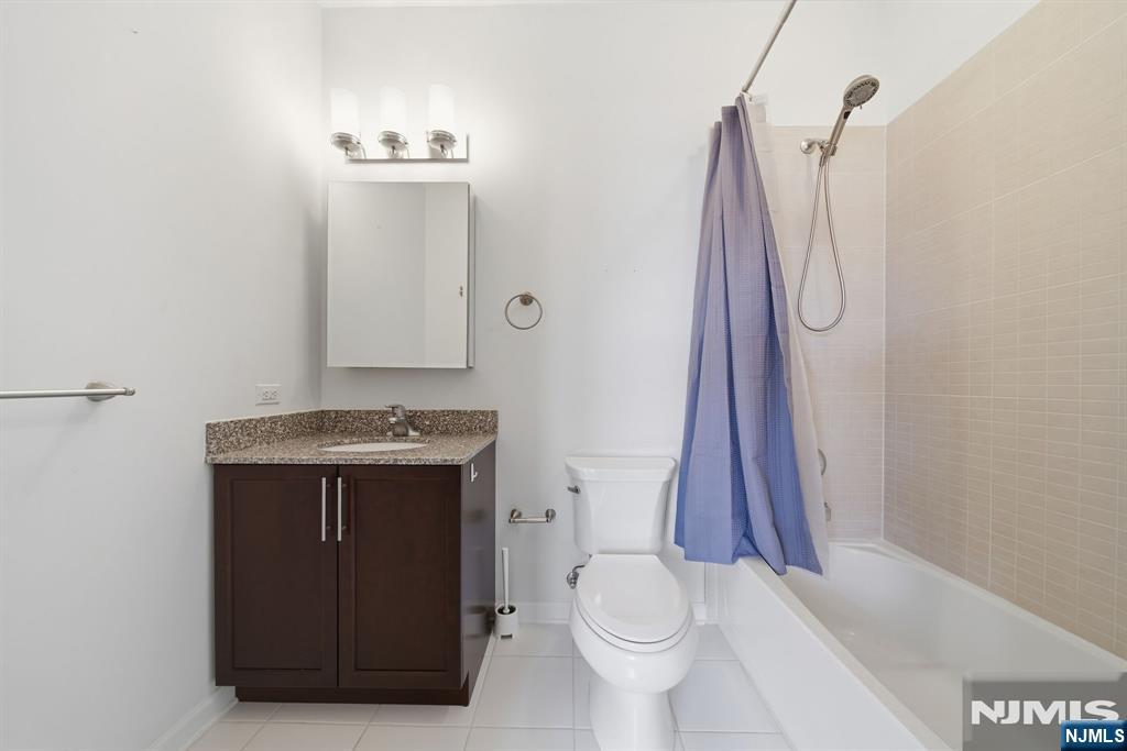 Bathroom with a dark wood vanity and granite countertop beside a tub with a blue shower curtain.