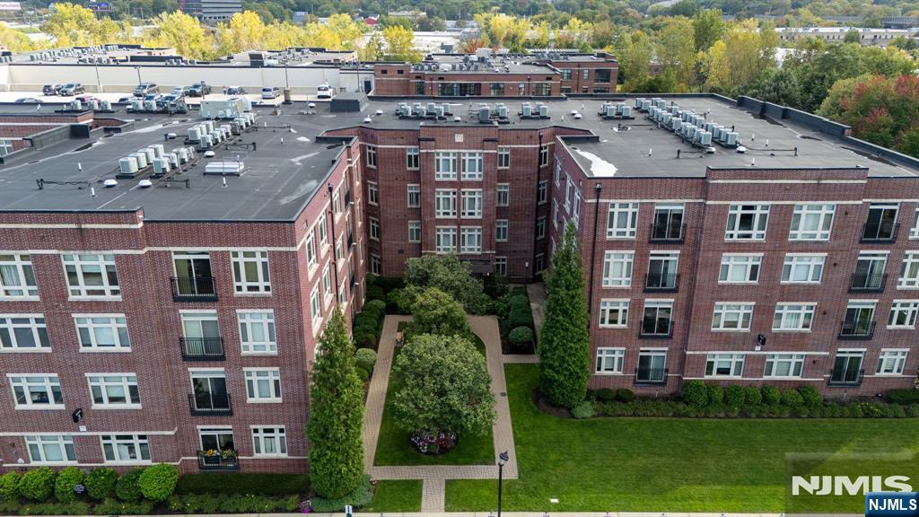 Aerial view of a red-brick residential building surrounding a landscaped courtyard and lawn.