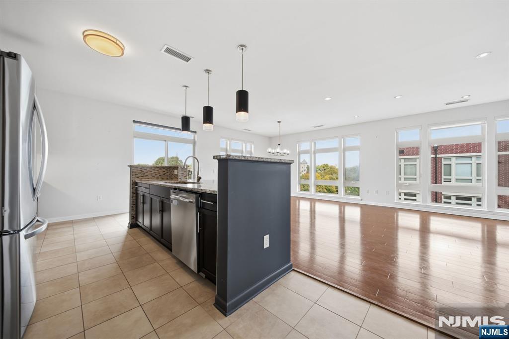 Open kitchen with a large dark island, stainless steel appliances, and windows overlooking the living area.