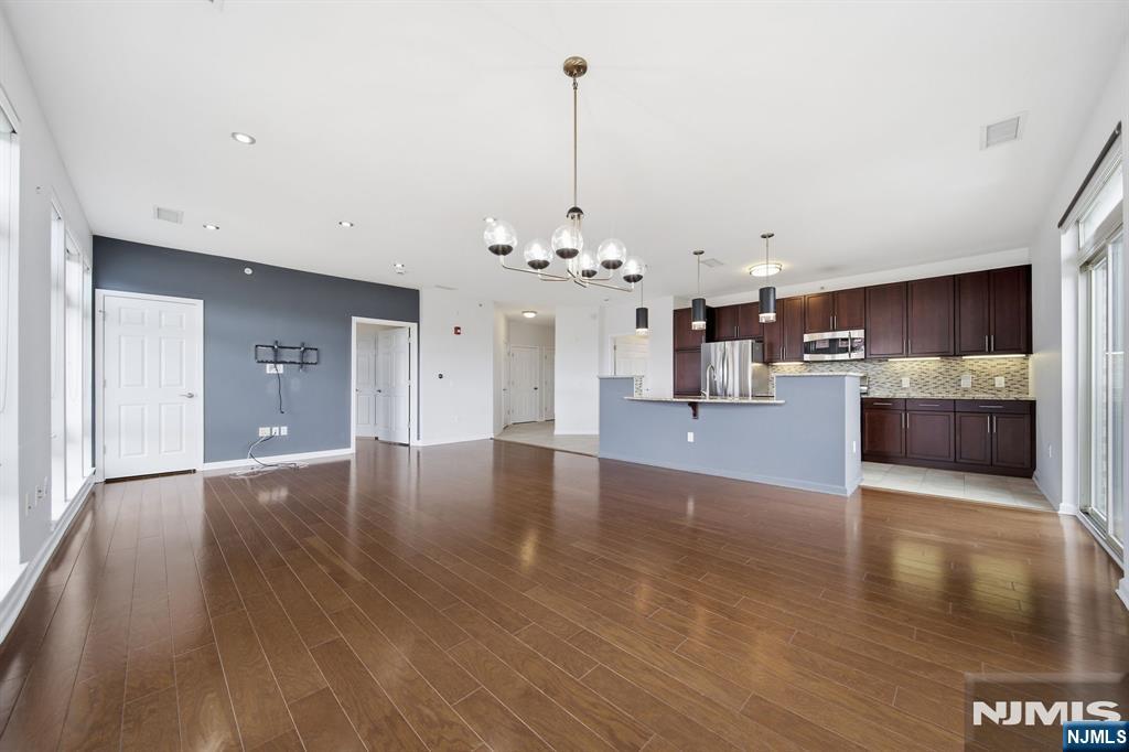 Open-plan living area with dark wood floors, a blue accent wall, and an adjoining kitchen.