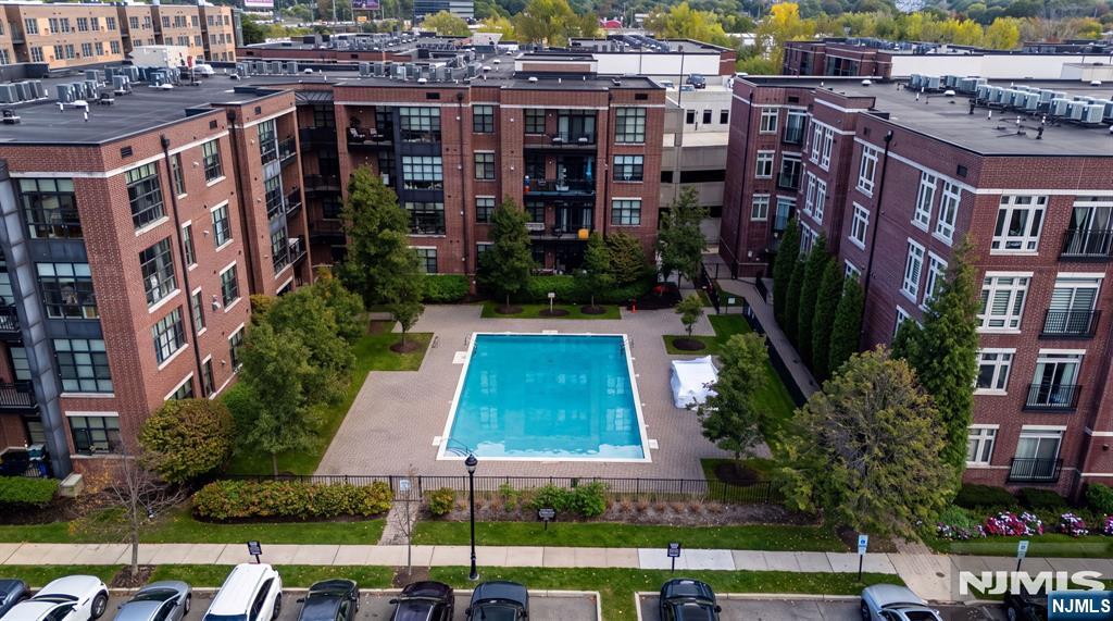 Aerial view of a brick apartment complex surrounding a courtyard pool and landscaped patio.