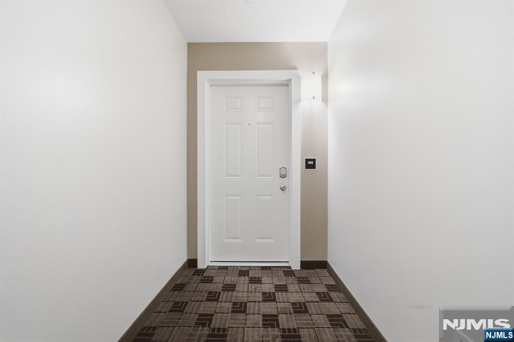 Apartment hallway ending at white door 410, with patterned carpet.