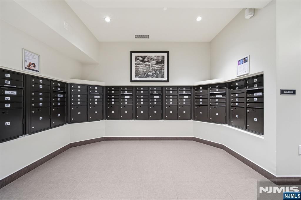 Mailroom with curved rows of black mailboxes and framed artwork.