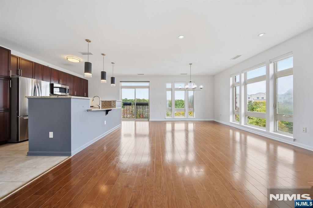 Open-plan living area and kitchen with hardwood floors, a breakfast bar, and large windows.