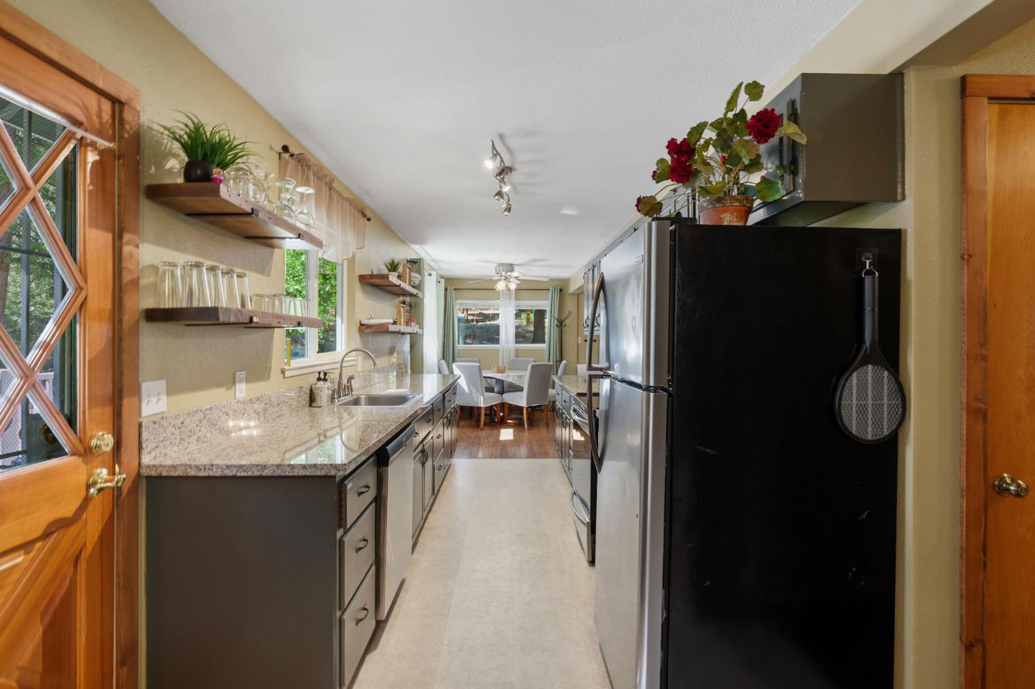 Long kitchen with granite counters, dark cabinets, stainless appliances, and a dining area by the windows.