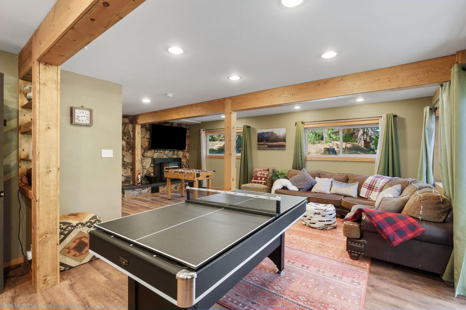 Living and game room with a ping-pong table, sectional sofa, and stone fireplace.
