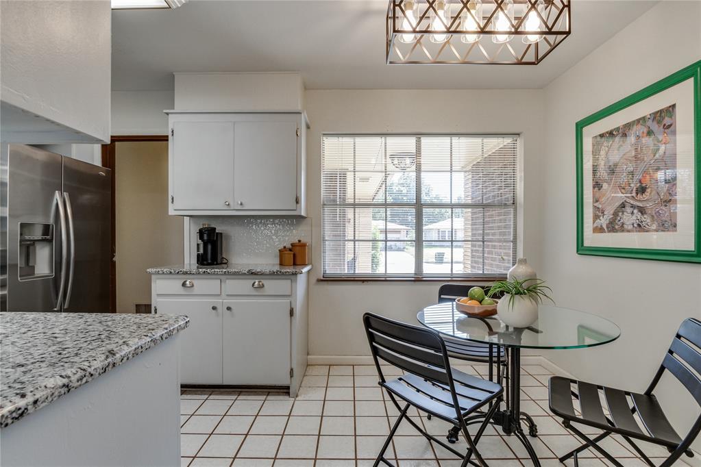 Kitchen and dining area with white cabinets, granite counters, and a glass table by the window.
