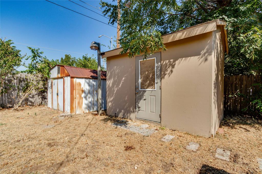 Two backyard storage sheds, including a large beige shed and a smaller rusted metal shed.