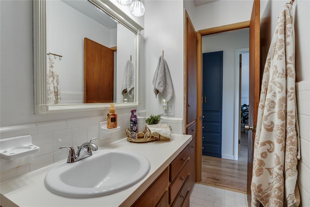 Bathroom vanity with a large mirror, oval sink, and wood cabinetry beside an open doorway.