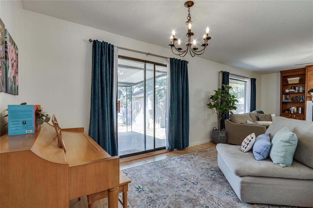 Living room with a gray sectional, wooden piano, and blue-curtained sliding glass doors.