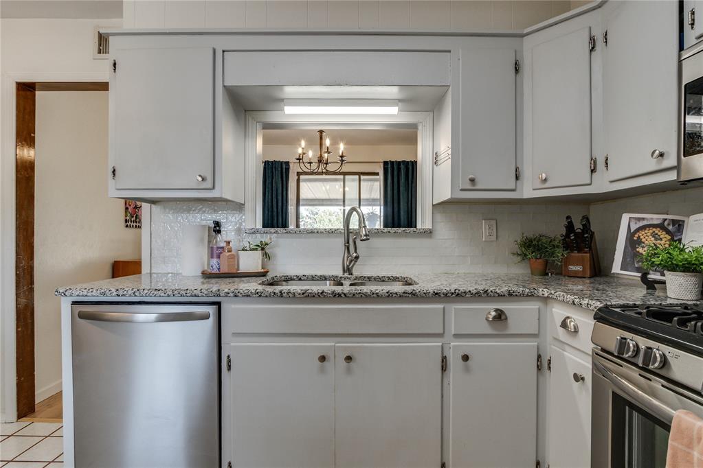 Kitchen with white cabinets, granite counters, stainless appliances, and a pass-through window.