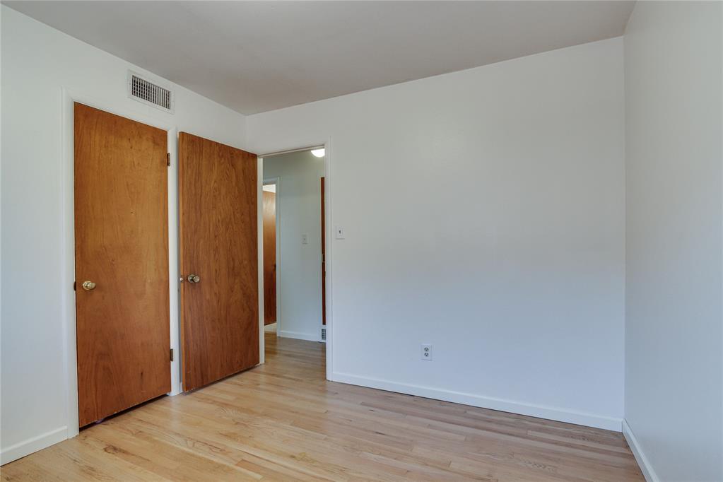 Empty room with pale wood flooring and two open wooden doors.