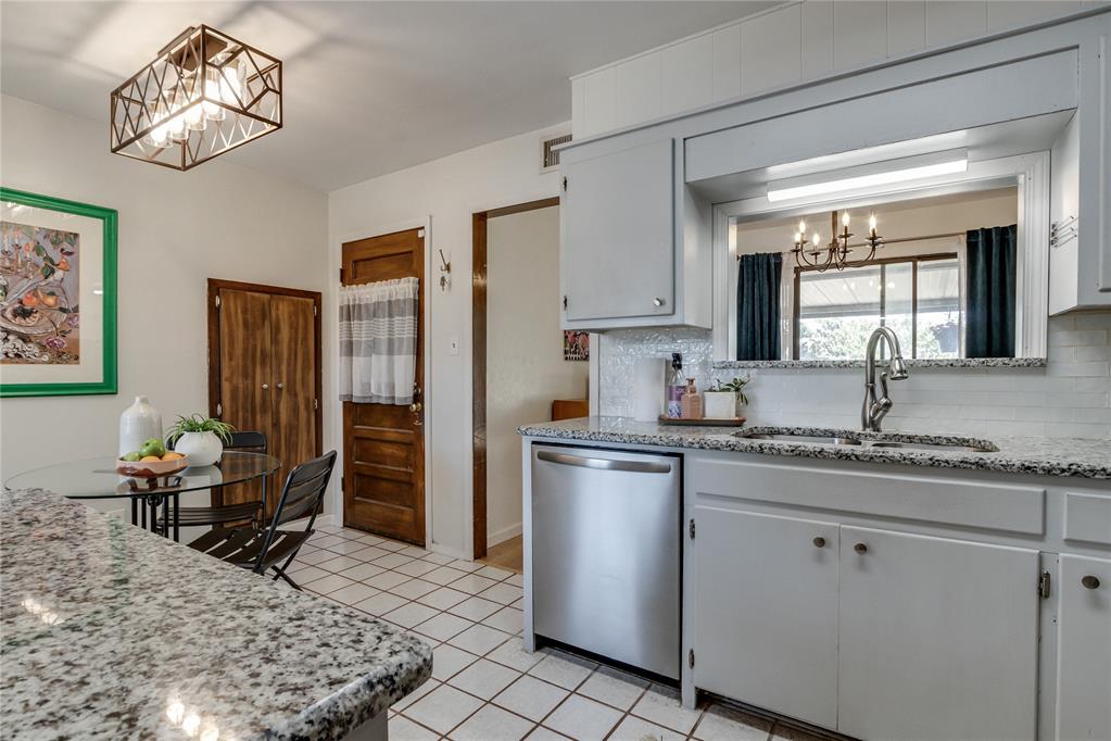 Kitchen with granite counters and white cabinets, opening to a small dining nook.