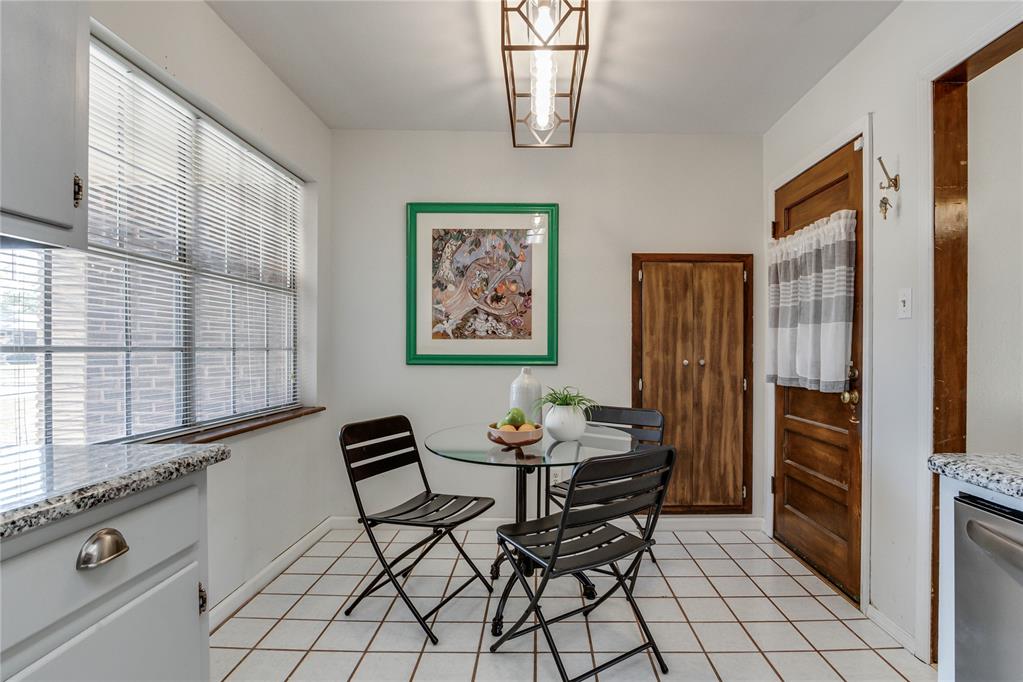 Kitchen dining nook with a glass table, black chairs, and a large window with blinds.