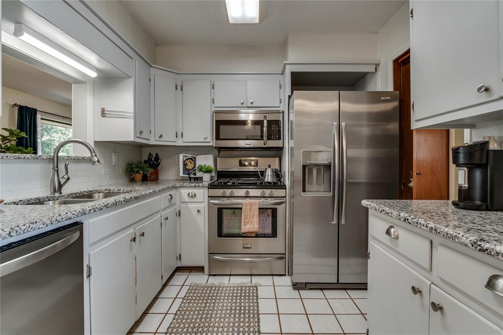 Kitchen with white cabinets, granite counters, and stainless steel appliances.