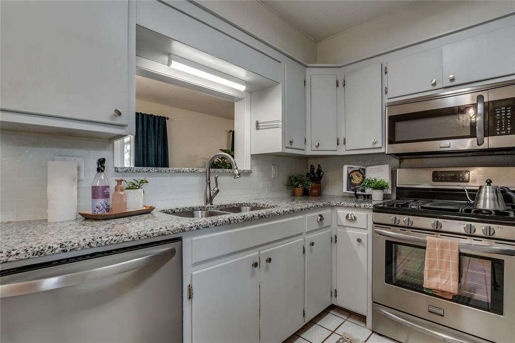 Kitchen with white cabinets, granite countertops, and stainless steel appliances.