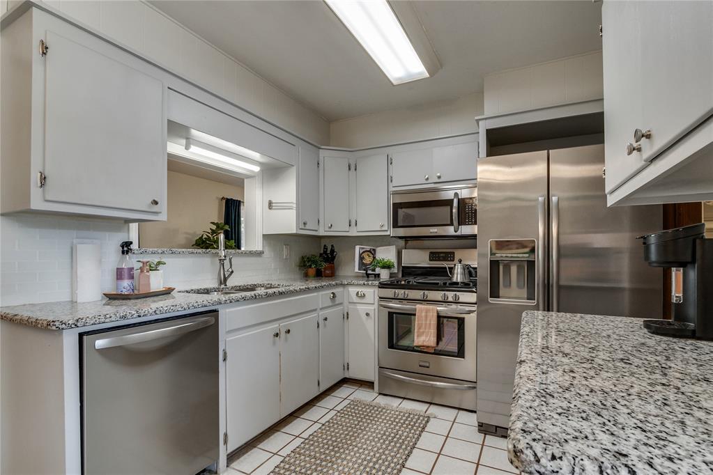 Kitchen with granite counters, white cabinets, and stainless steel appliances.