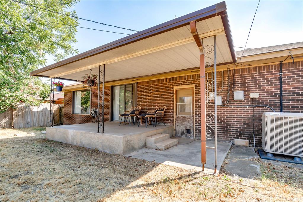 Brick home’s covered back patio with outdoor seating and decorative metal supports.