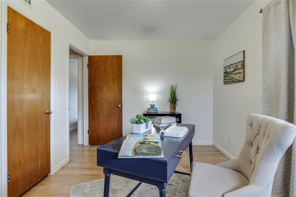 Home office with a dark blue desk, white chair, and two open wooden doors.