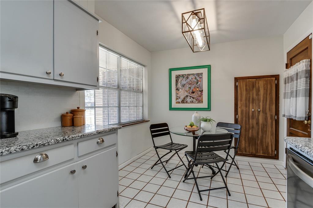 Kitchen with white cabinets and granite counters, plus a glass dining table and black folding chairs.
