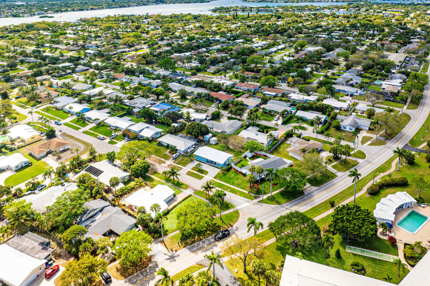 Aerial view of a leafy residential neighborhood beside a broad waterway.