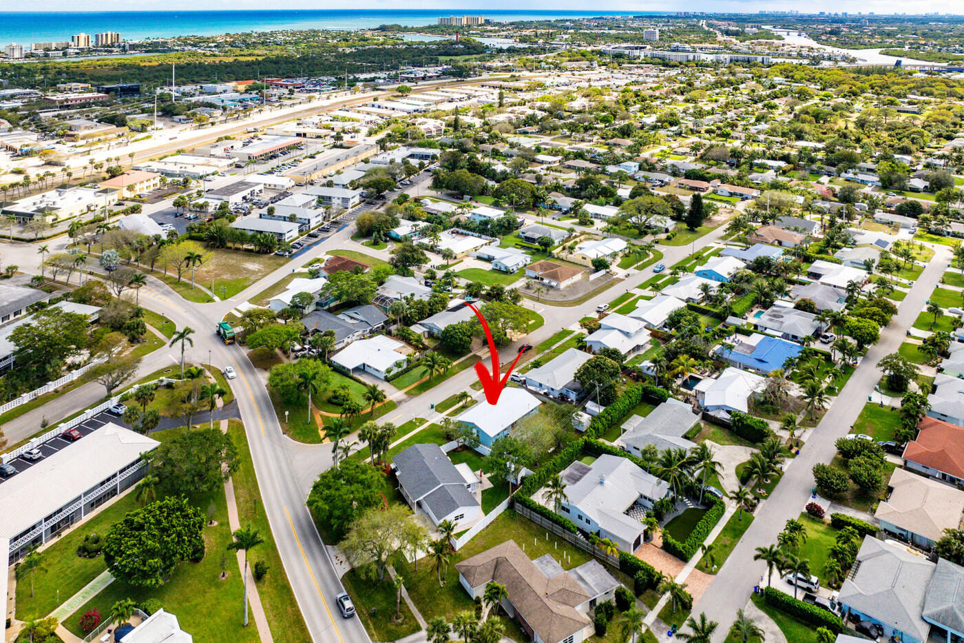 Aerial view of the home marked by a red arrow in a coastal neighborhood near the ocean.
