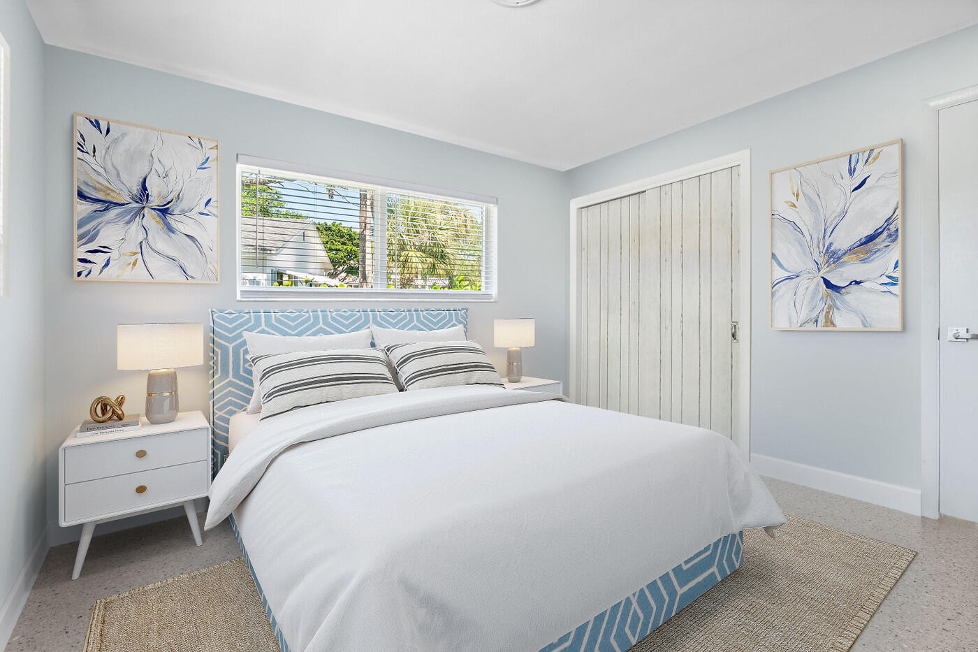 Bedroom with a blue patterned headboard, white bedding, and floral wall art.