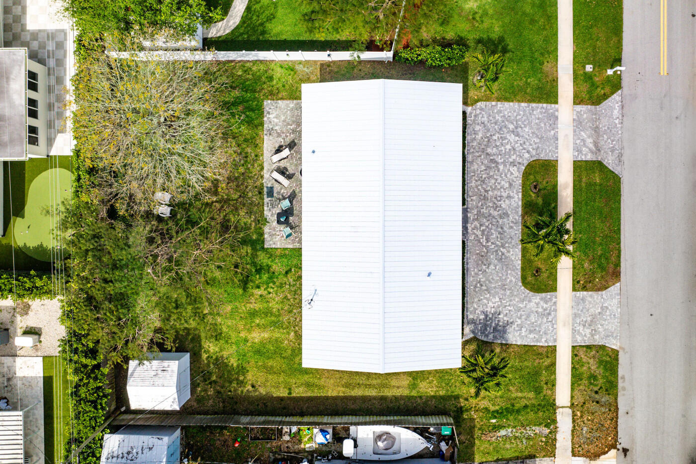 Overhead view of a home and landscaped lot, with a paved driveway and a boat beside the property.
