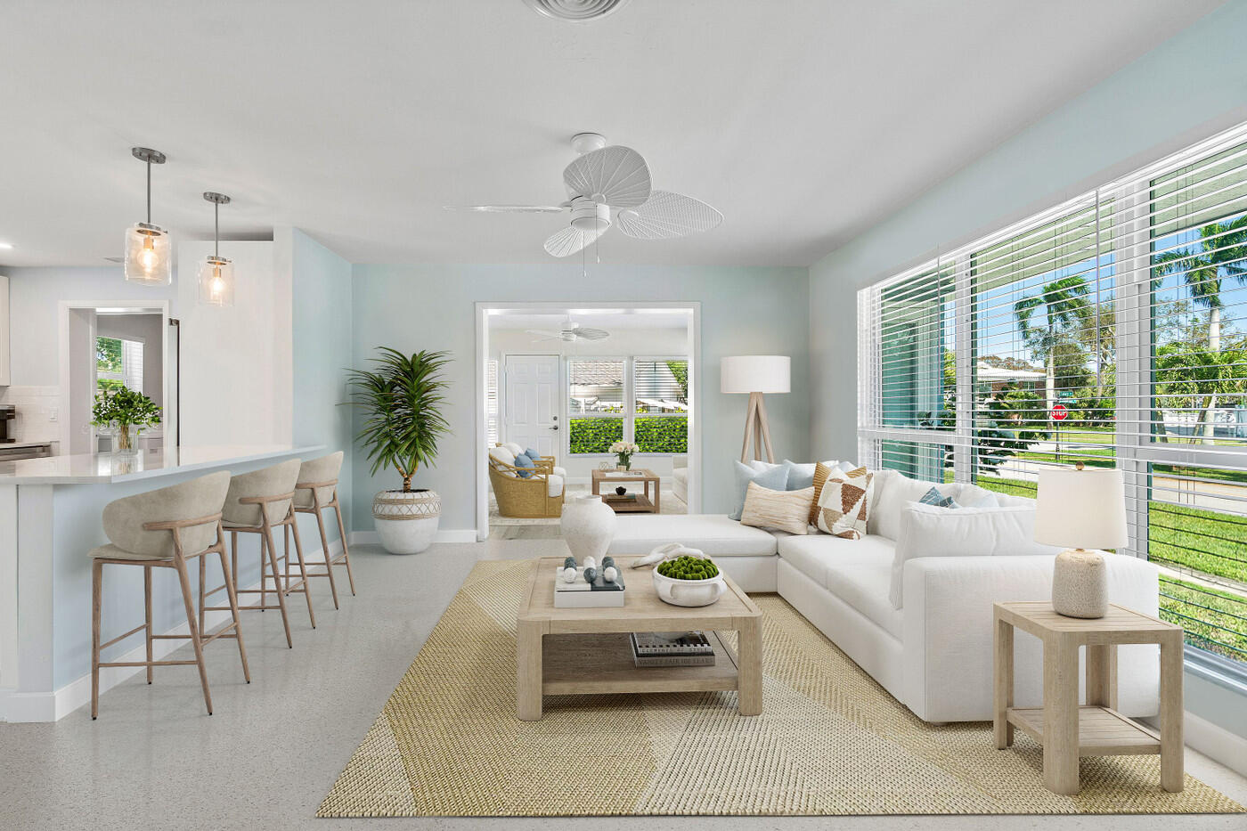 Bright living room with a white sectional, woven rug, and open kitchen with bar seating.