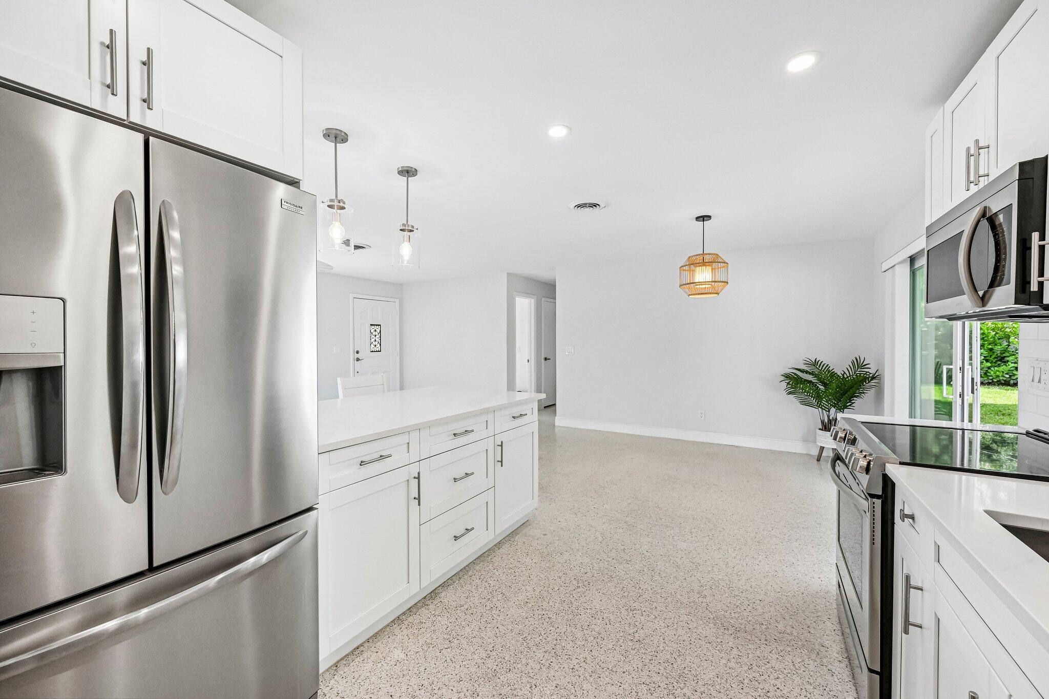Bright kitchen with white cabinetry, stainless steel appliances, and a central island.
