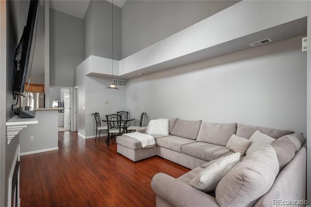 Living room with a large gray sectional, reddish wood floors, and vaulted ceilings.