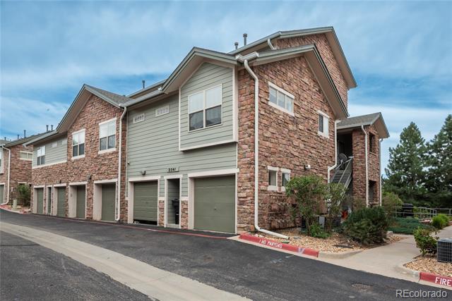 Multi-unit residence with brick and sage-green siding, garage doors, and an exterior stairway.