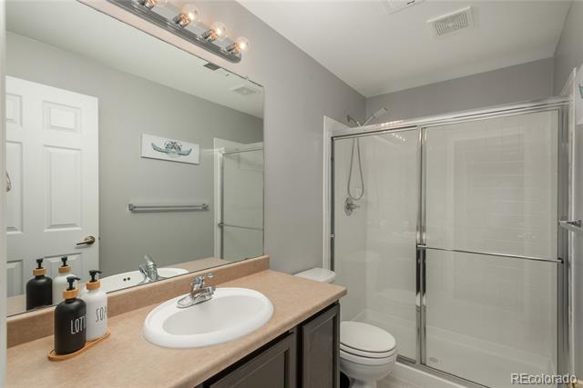 Bathroom with a beige vanity countertop and glass-enclosed shower.