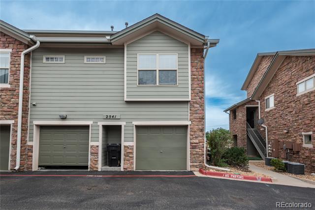 Attached home exterior with gray siding, brick accents, and two garage doors.