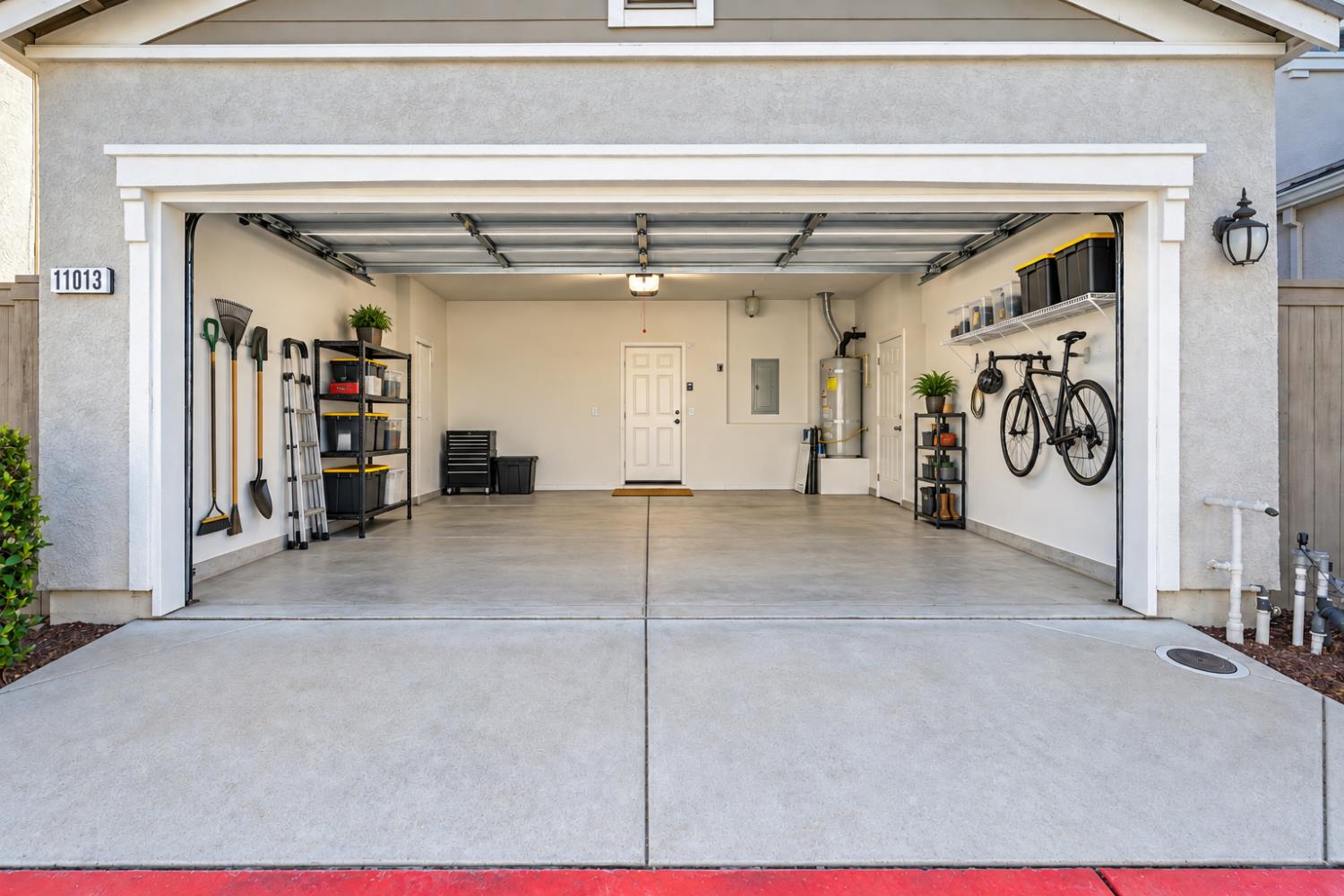 Open garage with organized storage racks, wall-mounted bicycle, and clean concrete floor.