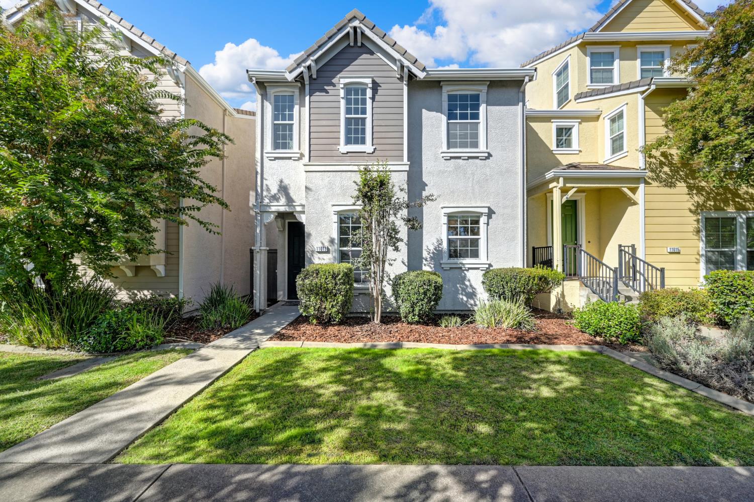Gray two-story home with white trim, a recessed entry, and landscaped front lawn.