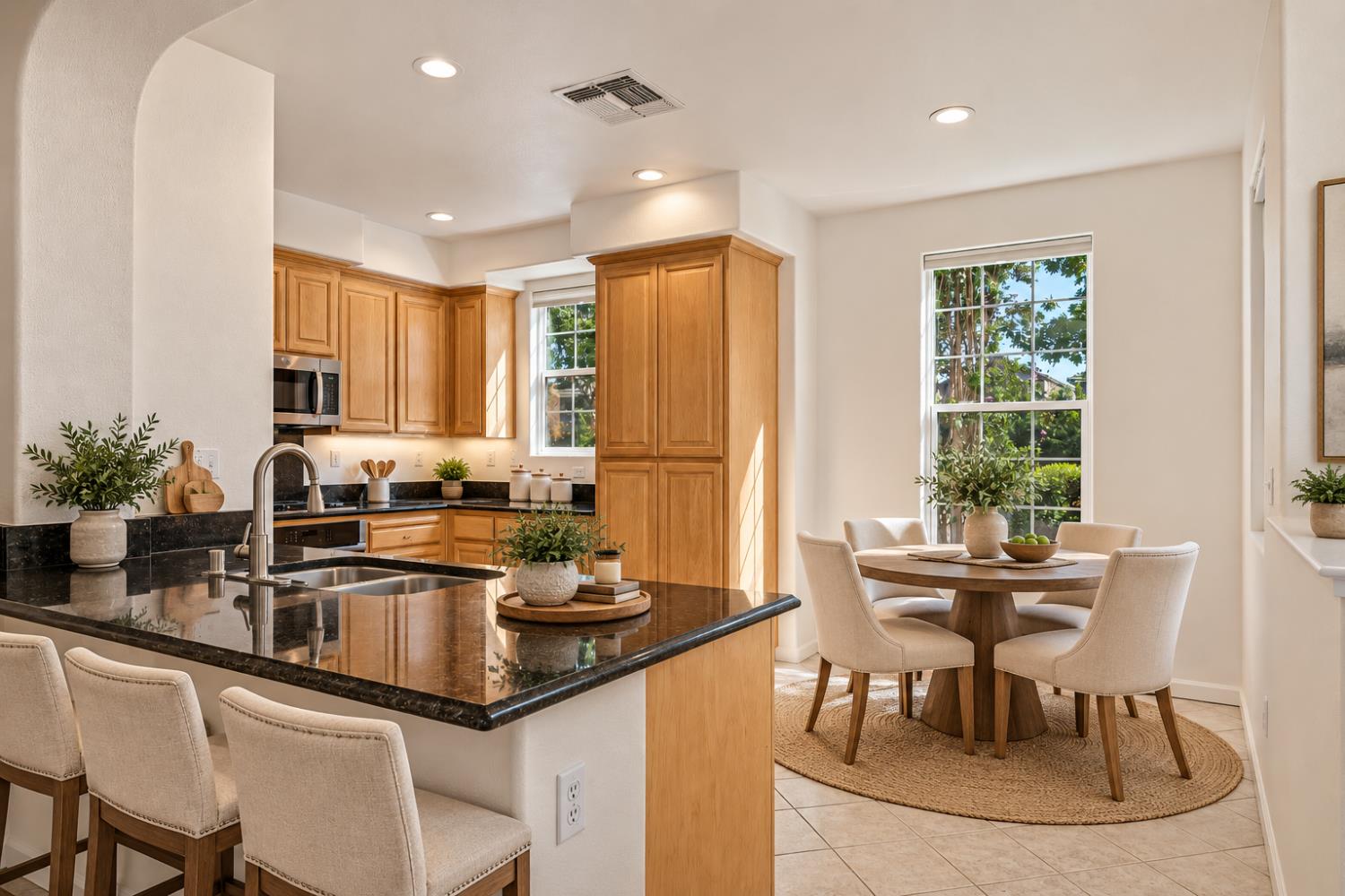 Kitchen and dining area with a granite island, wood cabinets, and a round table by the windows.