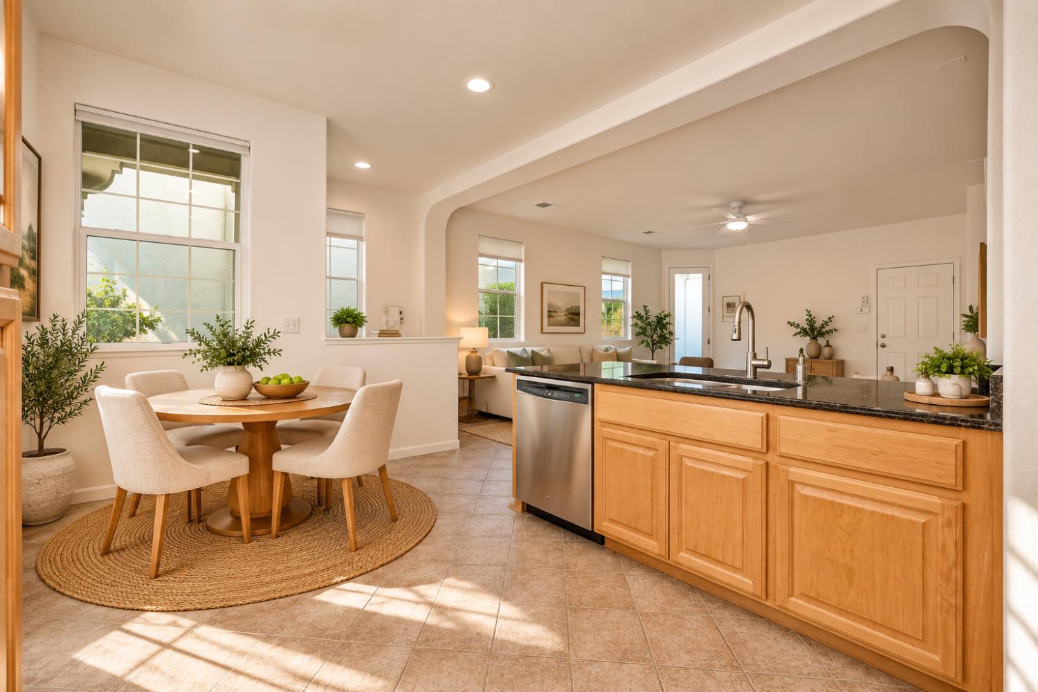 Open-plan kitchen and dining area with a black island countertop and round table by large windows.