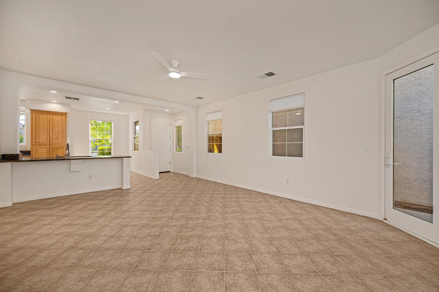 Open living and dining area with beige tile floors, a ceiling fan, and a kitchen breakfast bar.
