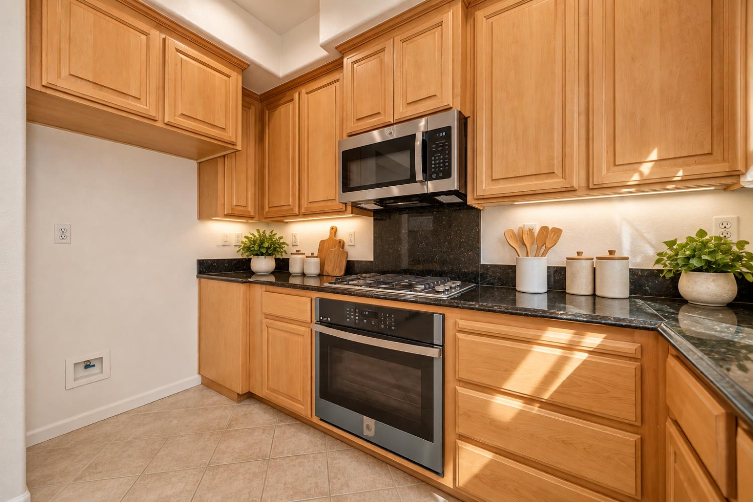 Kitchen with wood cabinets, black stone counters, and stainless steel appliances.