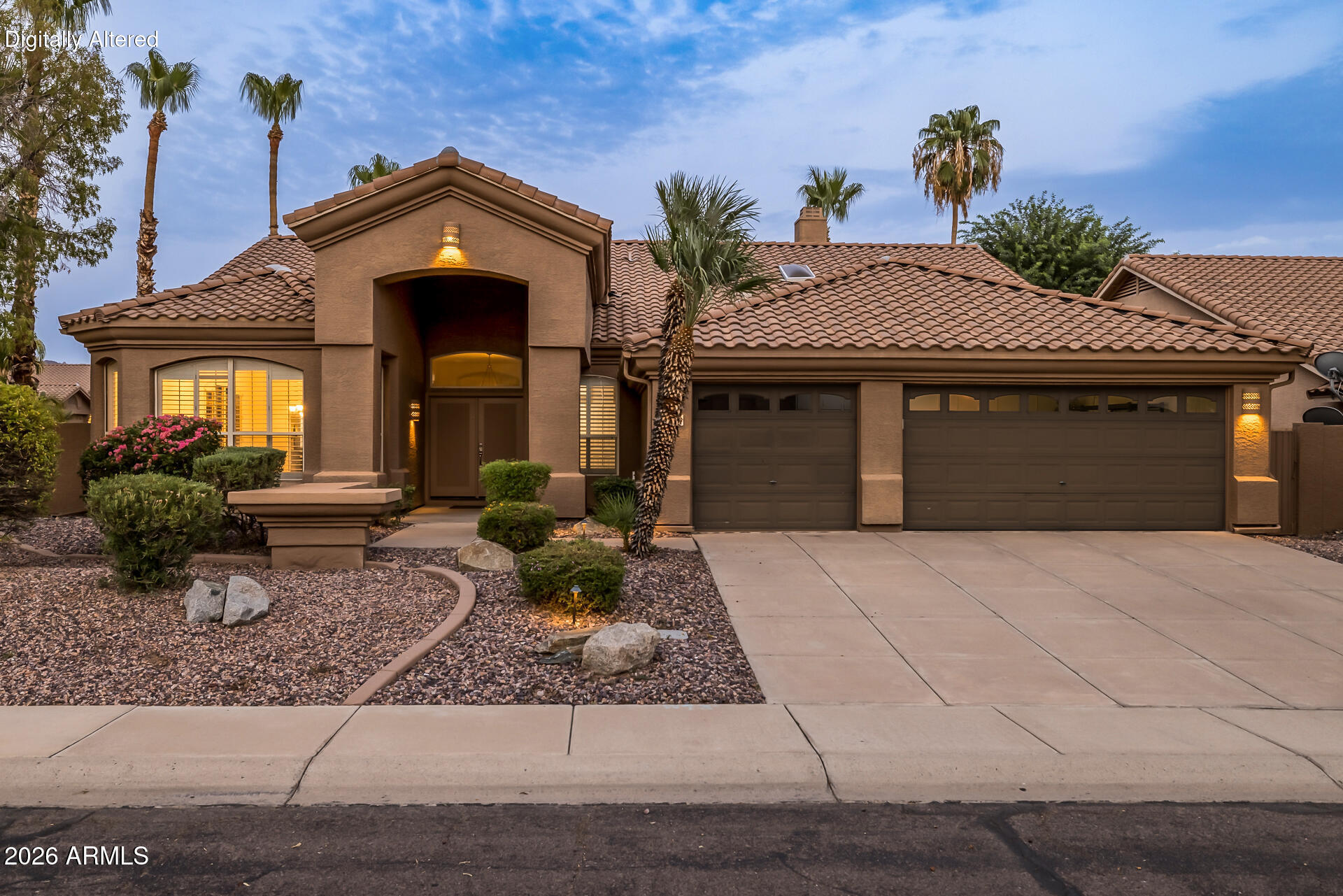 Stucco home with a tiled roof, desert landscaping, palm trees, and a three-car garage.