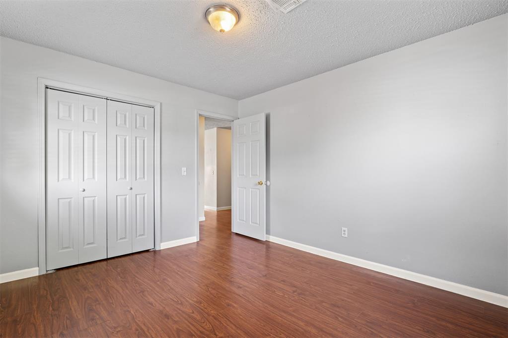 Empty room with wood-look flooring, double closet doors, and an open doorway.