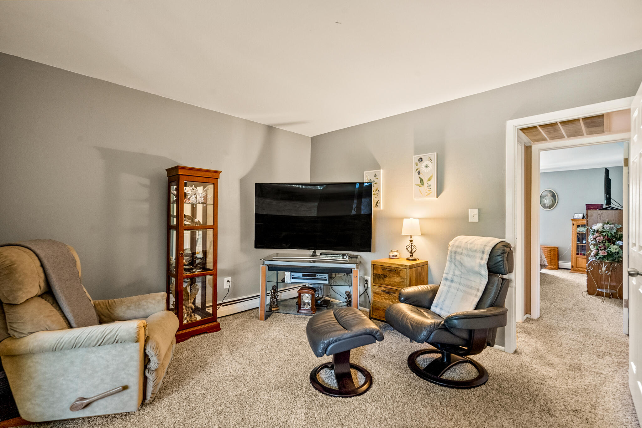 Furnished living room with a television, glass display cabinet, and leather recliner.
