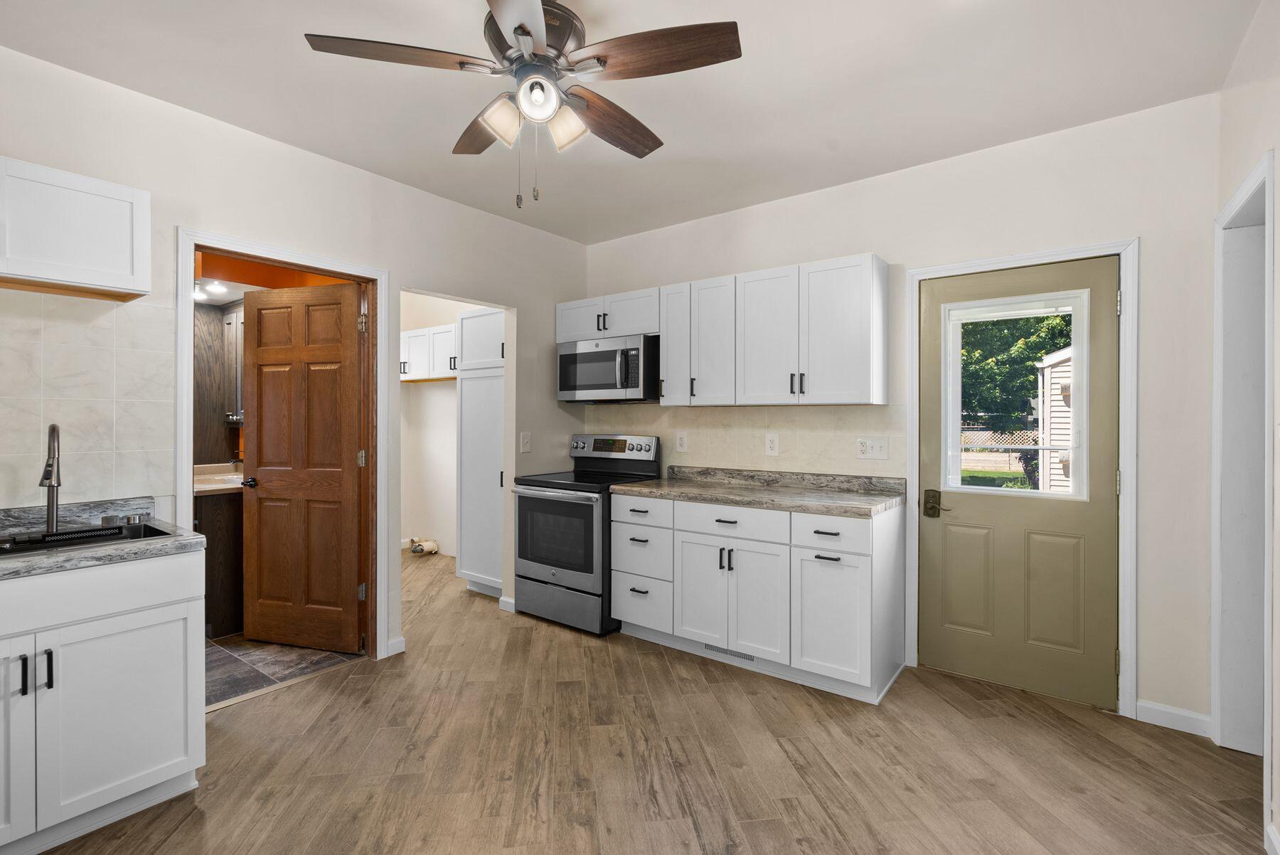 Kitchen with white cabinets, stainless steel appliances, and a backyard-facing door.